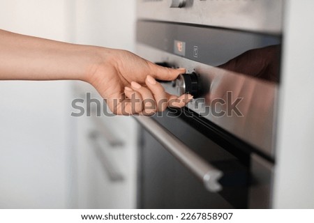 Unrecognizable Woman Turning Knob On Modern Oven In Kitchen, Young Female Adjusting Temperature On Electric Stove While Cooking At Home, Controlling Regime Of The Burner, Closeup Shot Royalty-Free Stock Photo #2267858907