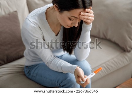 A sad woman holds a pregnancy test in her hand. Unwanted pregnancy concept. Royalty-Free Stock Photo #2267866345