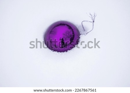 New Year's atmosphere. Christmas holiday. Winter picture. Christmas toys in the snow. Purple Christmas balloon.