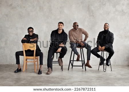 Young happy men against background of gray concrete wall. Multiethnic group of people. Fashion male models