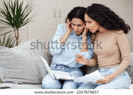 Women look at the laptop and do not understand why they cannot do the operation.
