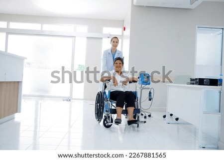 Smiling female doctor caring for an elderly woman patient sitting in a wheelchair