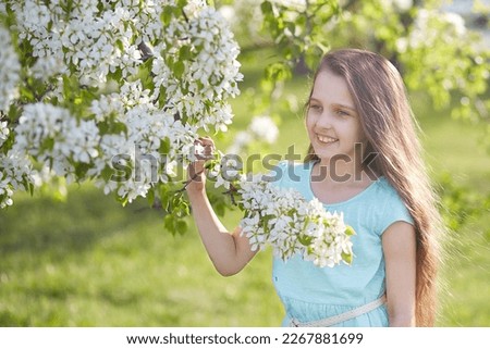 A smiling young girl in a blooming apple orchard.