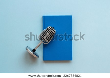 Record an audiobook or podcast concept. Book and microphone, top view.