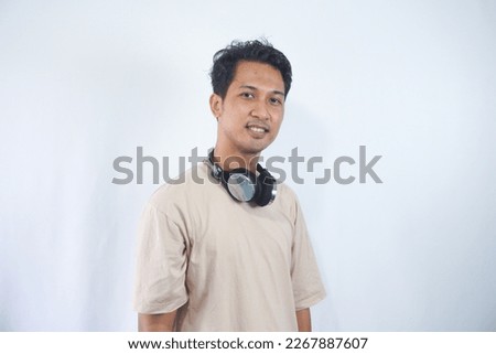 Handsome Asian man with headphones wearing cream t-shirt, Smiling and look at camera. isolated on white Background