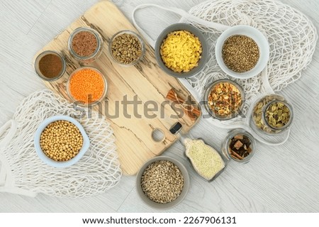 Various organic foods in glass jars and bowls on a white wooden background. Shopping and storage farm products. Top view. Copy space.