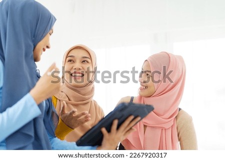 Group of a beautiful smart Asian muslim woman standing in the room and having a discussion together. Modern muslim society concept, women muslim student talking. Royalty-Free Stock Photo #2267920317