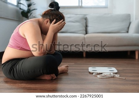 Stressful Asian overweight woman sad of dieting Weight loss fail.
 Royalty-Free Stock Photo #2267925001