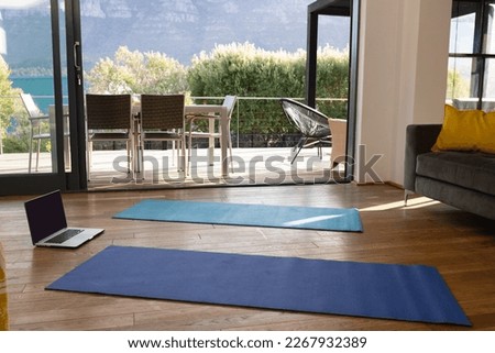 General view of luxury interior of living room with yoga mats and laptop. House interior and design concept.