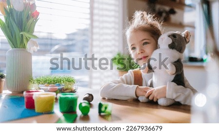 Portrait of little girl with bunny ears, bunny soft toy, celebrating easter.
