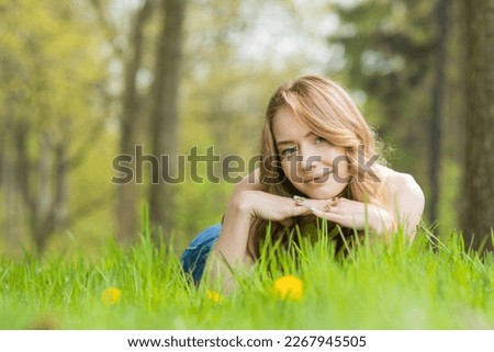 Pretty woman lying down on dandelions field happy cheerful girl resting on dandelions meadow, relaxation outdoor in springtime, vacation