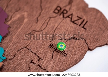 The country of Brazil on the world map, marked with a metal button in the form of the flag of Brazil, a wooden three-dimensional map of the world on a white background, macro, close-up, shallow depth  Royalty-Free Stock Photo #2267953233