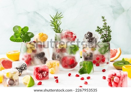 Refreshing drinks with ice cubes with fruits and citrus fruits, ice with blackberries and raspberries, gooseberries and currants, with mint, a jug of water and citrus fruits Royalty-Free Stock Photo #2267953535