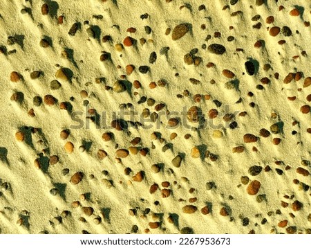 small stones and shadows on the sand by sea. texture sand and stones as a background