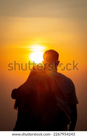 Silhouette of a young couple watching the sunset during twilight on a high mountain and embracing happily. Happy couple embracing each other with love and friendship and kindness for each other.