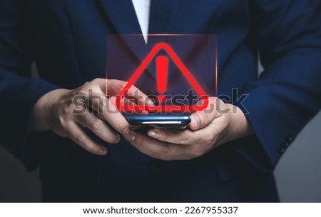 Businessman using smartphone with warning triangle showing a system error. Concepts of system maintenance, security, anti-virus, and anti-hacking access to critical data. Royalty-Free Stock Photo #2267955337