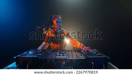 Cool female asian dj is working in a nightclub, standing at turntables, creating a dance music set - nightlife concept  Royalty-Free Stock Photo #2267970819