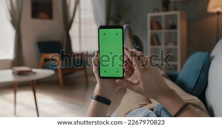 Close up shot of man lying on couch and using smart phone with chroma key green screen, doing various taps, swipes and scrolls - technology, communication 