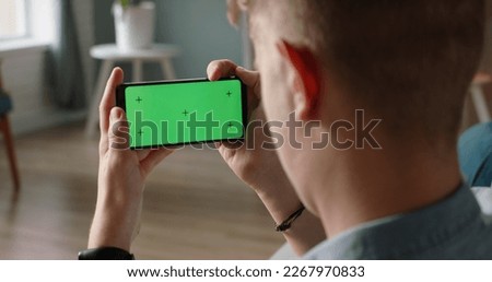 Man using a smart phone with mock up green screen, talking while having an online conference - online education, communications concept close up