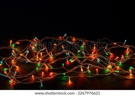Christmas background with lights and free text space. Christmas lights border. Glowing colorful Christmas lights on black background. New Year. Christmas. Decor. Garland.
