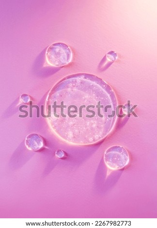 round drops of transparent gel serum on pink background