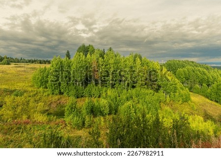 a small forest on top of a hill against a cloudy sky, Pinezhsky district Krasnaya Gorka Arkhangelsk region. travel and tourism. Royalty-Free Stock Photo #2267982911