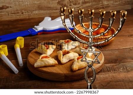 gometashi cookies with mishloach manot jam for Purim laid out on a wooden board next to the menorah rattles and whistle. horizontal photo