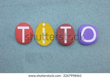 Tito, masculine given name composed with multi colored stone letters over green sand