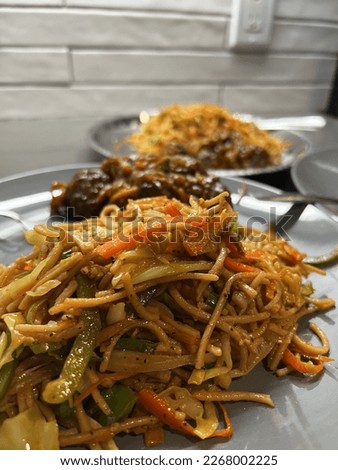 The noodles are stir-fried with  cabbage, carrots, onions, and bell peppers, giving the dish a vibrant and colorful appearance. The seasoning may include soy sauce, vinegar and chili sauce.