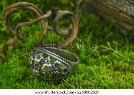 bright forest moss blackened  silver ring with flowers  and vine weaving day  Royalty-Free Stock Photo #2268002529