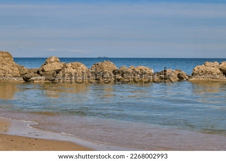 Blue sea, blue sky with clouds and high stones