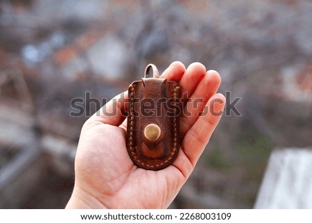 Vintage style mini size leather knife sheath in hand. Small folding knife sheath made by rustic leather.  Royalty-Free Stock Photo #2268003109