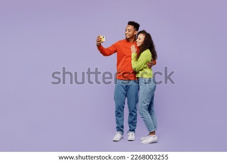 Full body side view young couple two friends family man woman of African American ethnicity wear casual clothes doing selfie shot mobile cell phone together isolated on plain light purple background