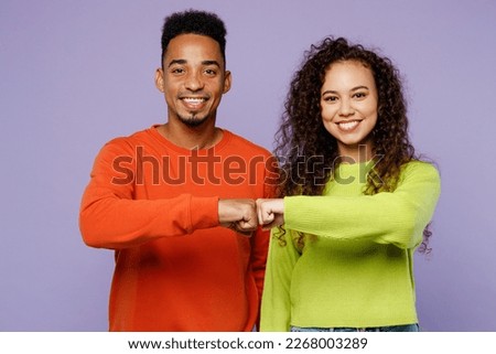 Young smiling happy couple two friends family man woman of African American ethnicity wearing casual clothes together meet each other give fist bump isolated on pastel plain light purple background Royalty-Free Stock Photo #2268003289