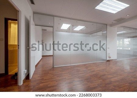 Offices of an empty office with technical ceilings, glass partitions and reddish floating flooring Royalty-Free Stock Photo #2268003373