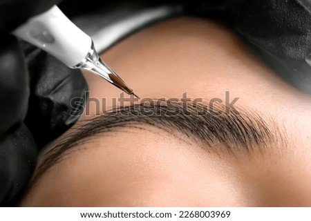 Eyebrows tattoo or Permanent Makeup. Detail of beautiful woman, eyebrow with nice black Brows In Beauty Salon. Beauty eyebrow upgrade procedure. Royalty-Free Stock Photo #2268003969