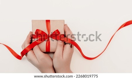 Hand red gift. Women's hands hold a present for christmas or valentine's day. Isolated on white background. View from above