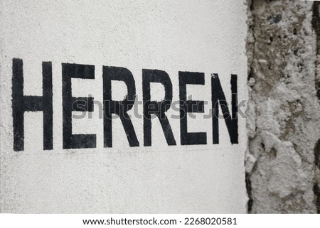 Black letters Herren on a white wall.
German word for men, sign for gentleman toilets
