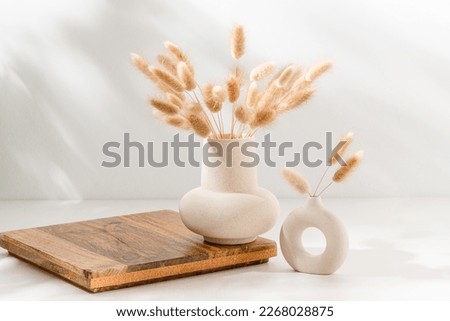 Vase set with dried lagurus grass on wooden podium with copy space on the table with shadows. Wooden display for home product presentation, scandinavian interior decoration