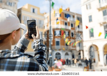 A teenager girl using a smartphone takes pictures of a festively decorated city