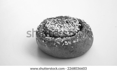 Isolated cinnamon bun on white background captured in black and white. 