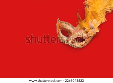 Golden Carnival mask against background in shades of red. Mardi Gras concept or New Years decoration. Festive background. Close-up