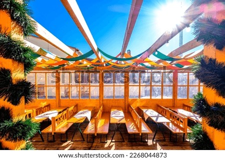 typical bavarian beergarden with wooden benches and tables - photo
