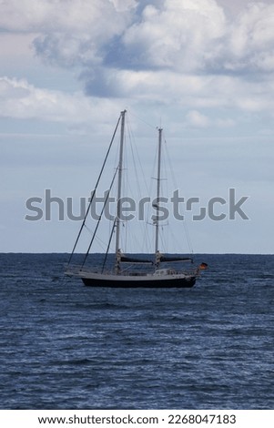 A vertical picture of a boat floating on water in the middle of an ocean