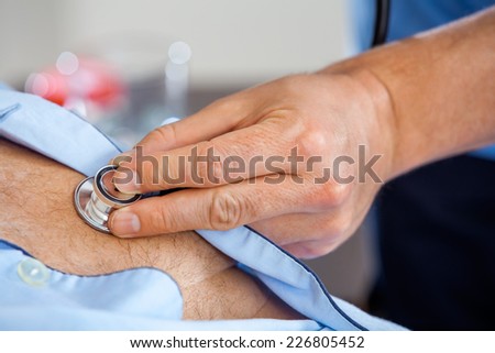 Closeup of male caretaker examining senior man with stethoscope at nursing home