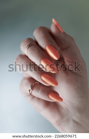 Female beautiful hand with long nails and a yellow orange nail polish