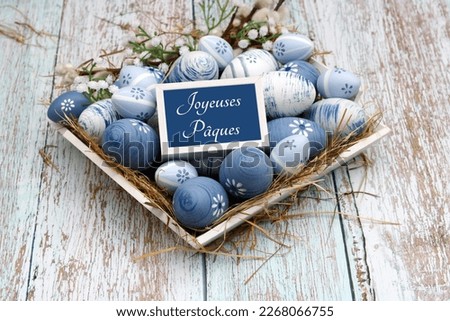 Easter greeting card: Blue Easter egg of a nest. French inscription means a happy Easter.