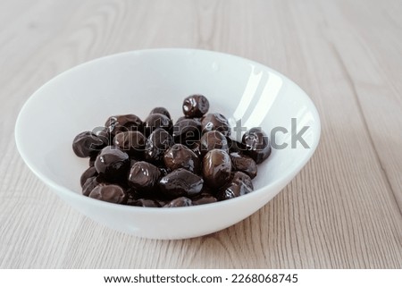 Black olives berries in white cup source of healthy polyunsaturated and saturated fats