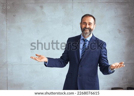 Portrait of a happy mature business professional standing with his arms crossed in modern office. Smiling businessman at his workplace. Successful Mature man with folded arms standing 