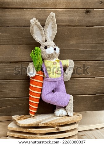 Cute Easter bunny with carrot on wooden background